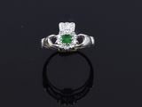 an emerald and diamond ring on a black surface