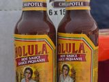 two bottles of hot sauce sitting on top of a table