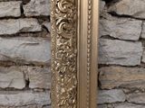 a gold framed mirror on a stone wall next to a brick wall