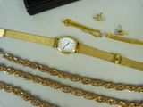 a lot of gold chains and a watch on a table