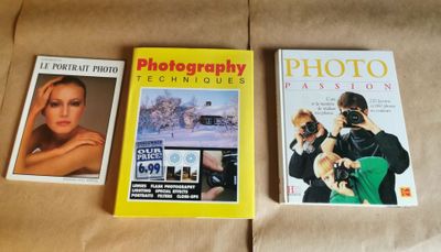 trois livres posés sur un lit, avec un appareil photo et un album photo