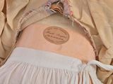 a white apron with a label on it on the back of a mannequin