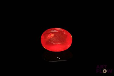 une image représentant une boule de verre rouge posée sur une surface noire