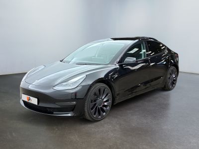 une Tesla Model 3 noire garée dans une pièce blanche