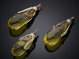 three yellow quartz and diamond pendants on a black surface