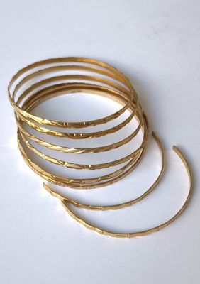 des bracelets rigides plaqués or empilés les uns sur les autres sur une surface blanche