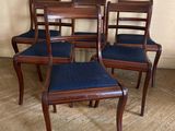 quatre chaises en bois avec des assises rembourrées bleues dans une pièce