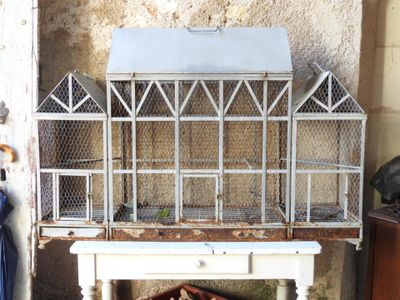 a bird cage on a table next to a potted plant