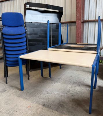 plusieurs chaises et une table dans un entrepôt où se trouve une pile de chaises