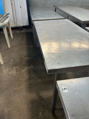 Plusieurs tables en acier inoxydable sont alignées dans une pièce