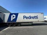 Le camion est garé devant le bâtiment ; il porte un logo bleu et blanc.