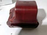 a brown leather camera case sitting on a white counter