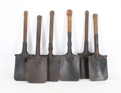 quatre vieux outils de jardinage sont alignés sur une surface blanche