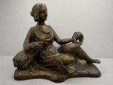 statue en bronze représentant une femme assise sur un rocher avec un chien