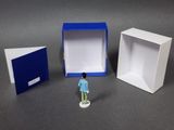 a small figurine of a man standing in front of a box