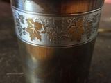 une tasse en métal ornée d'un motif, posée sur une table