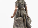 statue of a woman in a dress with a hat and a bag
