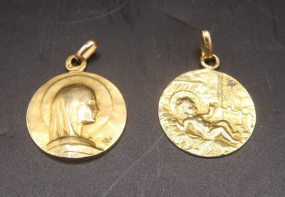 two gold medal pendants depicting a woman and a man