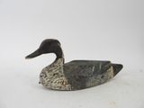 une image représentant un canard en bois posé sur une surface blanche