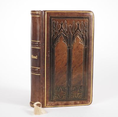 an old book with a wooden cover sitting on top of a white surface