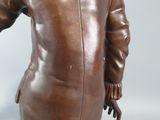 bronze statue of a man in a suit and hat holding a tennis racquet