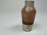 a brown and white vase sitting on a white surface