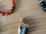several necklaces and bracelets on a wooden surface with a bead