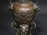 a bronze vase with a lion on it on a black background