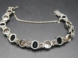 a close up of a silver bracelet with black and white stones