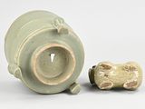 a green vase with a frog on it next to a bone
