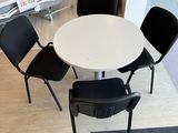 une table blanche et quatre chaises noires dans une pièce