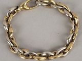 gros plan d'un bracelet en or et en argent sur une surface blanche