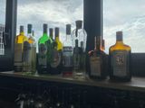 bottles of alcohol are lined up on a shelf in front of a window