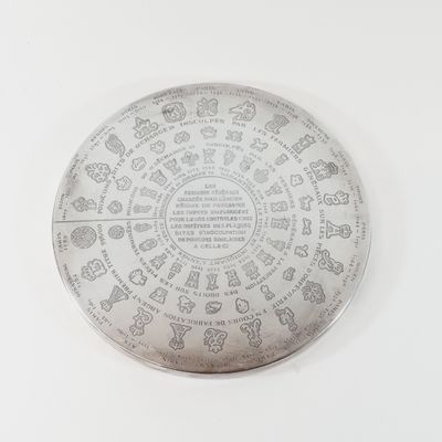 a silver plate with a design on it on a white surface