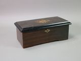 a small wooden box with a gold decoration on it
