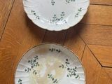 two plates with floral designs on them sitting on a wooden floor