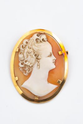 Une broche en or représente le profil d'une femme.