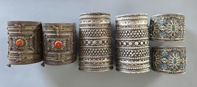 Plusieurs bracelets en argent sont disposés en rangée sur une étagère