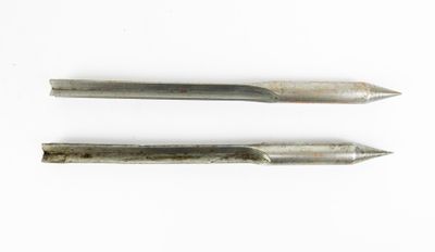 deux outils métalliques posés sur une surface blanche, sur fond blanc