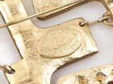 a close up of a gold plated brooch with a cross on it