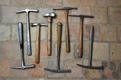 de nombreux types de marteaux différents disposés sur un mur de briques