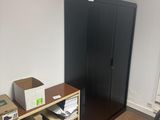 a black refrigerator in a room with many boxes on the floor