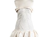 La robe est blanche et comporte une jupe à volants.