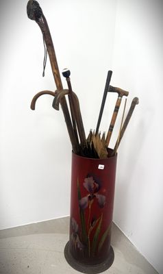 a red vase with a bunch of old walking sticks in it