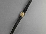 a close up of a watch on a gray surface with a black strap