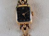an image of a black and gold watch on a white pillow
