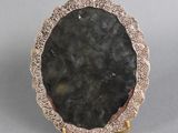 an image of a picture of a black stone in a gold plated frame