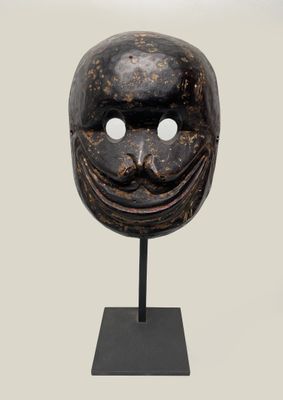 a wooden mask on a black stand with a white background