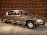 a brown car that is parked in front of a brick wall