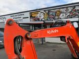 a red excavator that is parked in front of a building